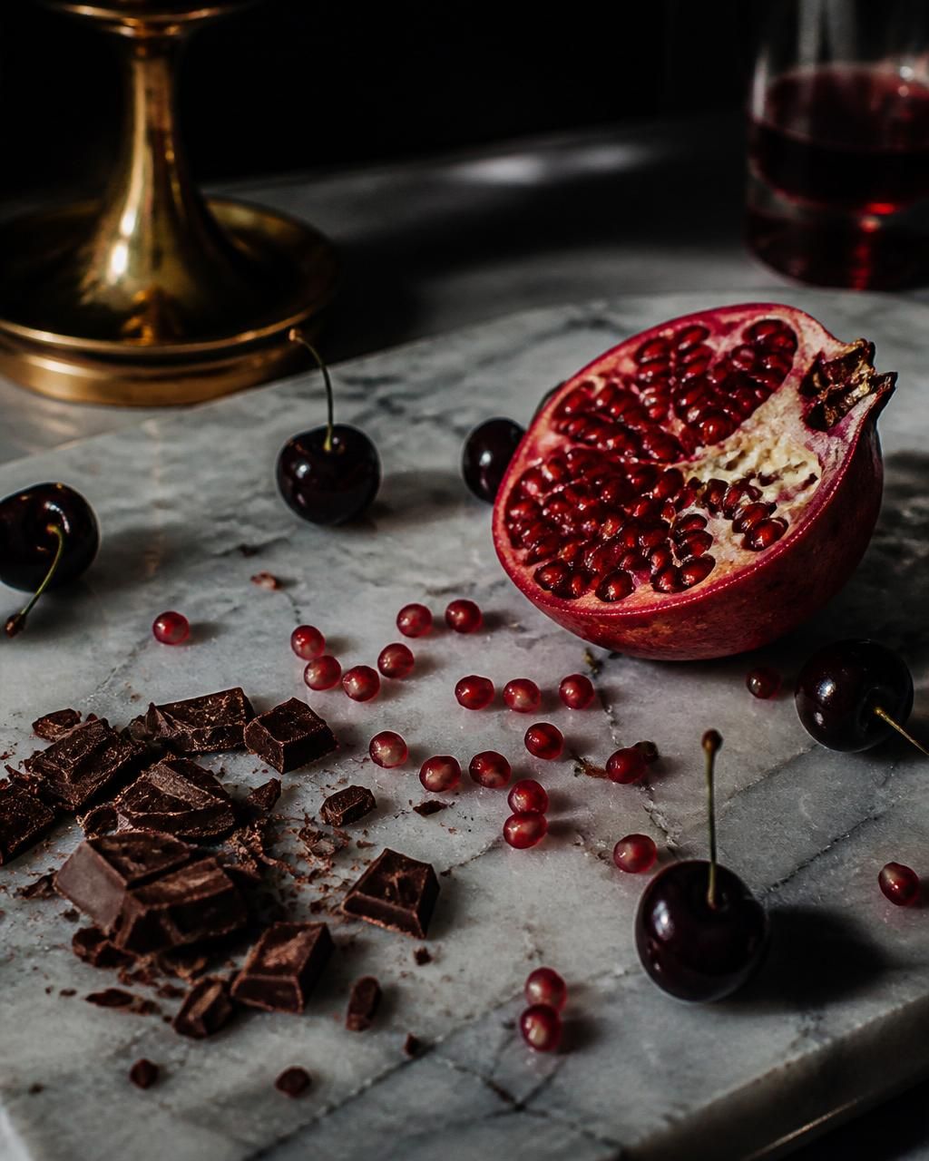 A halved pomegranate on a brass plate over dark walnut.