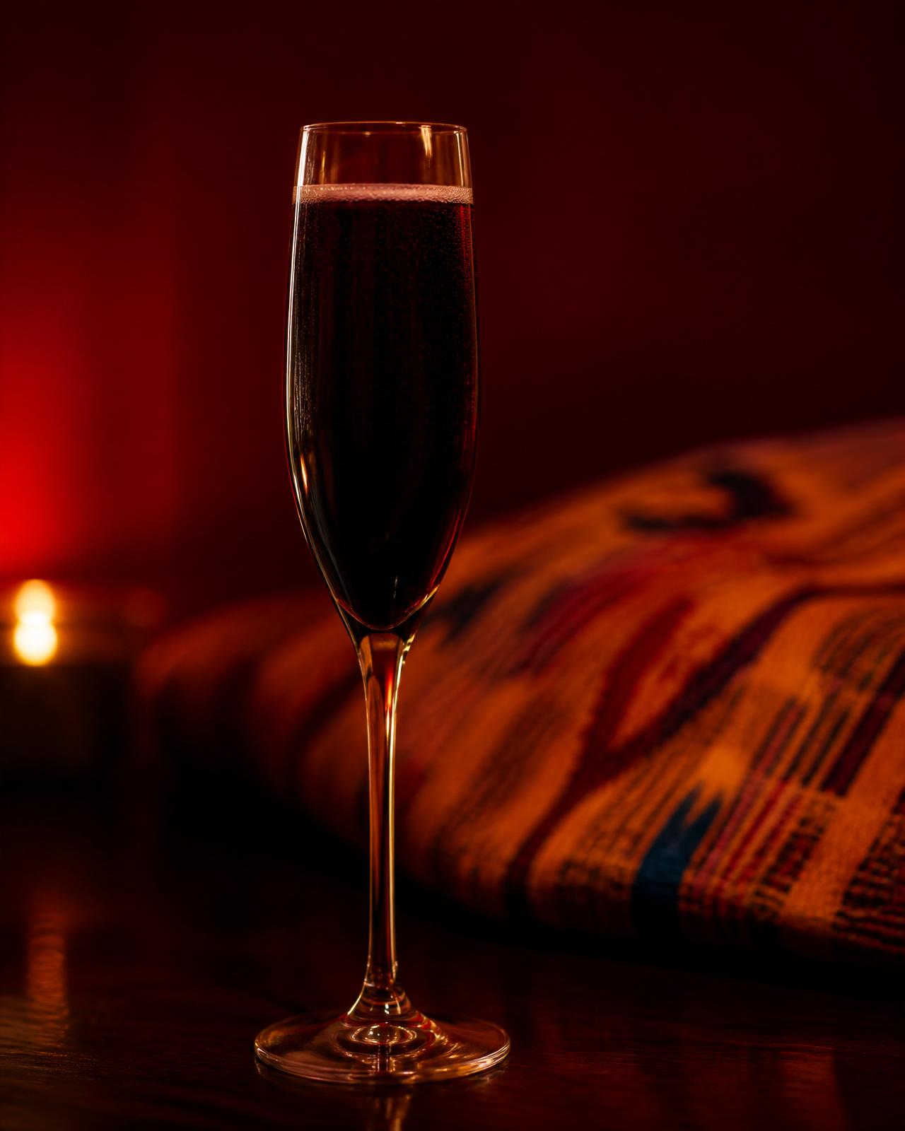 A single slender flute of dark crimson elixir, candlelit, no other glassware in frame.